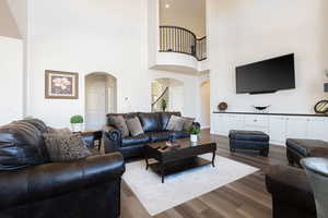 Living area featuring arched walkways, dark wood finished floors, and a high ceiling