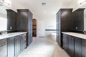 Full bathroom with two vanities, light tile patterned flooring, a freestanding bath, tile walls, and recessed lighting