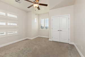 Unfurnished bedroom with light carpet, ceiling fan, and a closet
