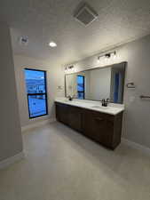 Primary bathroom featuring double vanity and a textured ceiling