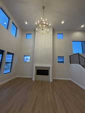 Living room with dark wood-type flooring, plenty of natural light, a high ceiling, a fireplace, and recessed lighting