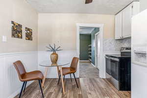 Dining space featuring light wood-style floors, wainscoting, and a textured ceiling