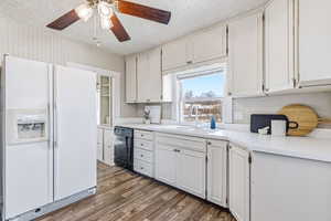 Kitchen with white fridge with ice dispenser, light countertops, a textured ceiling, dark wood-style floors, and white cabinets