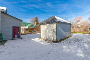 Snow covered structure featuring a shed