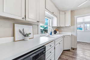 Kitchen featuring light countertops, white cabinetry, dark wood-style flooring, and dishwasher