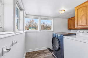 Laundry room featuring dark wood-type flooring, cabinet space, and washer and clothes dryer