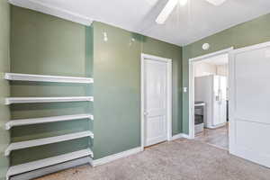Unfurnished bedroom featuring carpet, a ceiling fan, and white refrigerator with ice dispenser