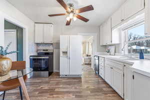 Kitchen featuring white cabinets, white refrigerator with ice dispenser, electric range, light countertops, and dark wood-style flooring