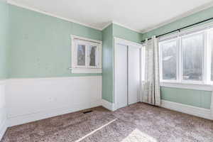 Unfurnished bedroom featuring ornamental molding, carpet floors, a closet, and wooden walls