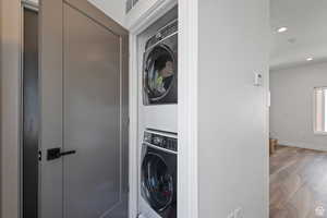 Washroom featuring wood finished floors, recessed lighting, and estacked washer and dryer