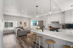 Kitchen featuring a kitchen bar, modern cabinets, pendant lighting, open floor plan, and backsplash