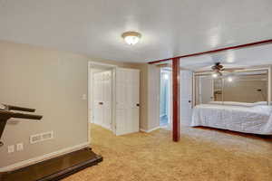 Bedroom featuring a textured ceiling, carpet flooring, and ceiling fan