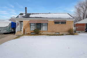 Snow covered front of property featuring brick siding