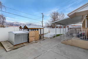 Fenced backyard featuring a patio, a mountain view, and a storage shed