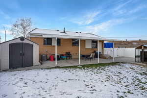 Back of house featuring a storage unit, a patio area, brick siding, and a gate