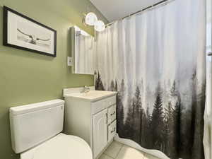 Full bathroom featuring a shower with curtain, vanity, and light tile patterned floors