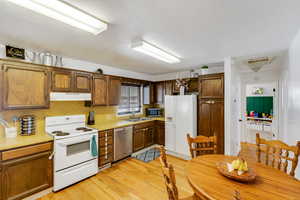 Kitchen with appliances with stainless steel finishes, light countertops, under cabinet range hood, light wood-type flooring, and cooling unit