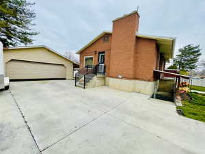 View of side of property featuring a chimney, an outbuilding, a garage, and brick siding