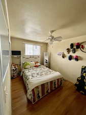 Bedroom featuring a textured ceiling, wood finished floors, and ceiling fan
