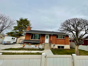 View of front of house featuring a gate, brick siding, a chimney, a fenced front yard, and a garage