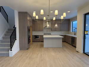 Kitchen featuring decorative light fixtures, light wood-type flooring, a kitchen island, tasteful backsplash, and recessed lighting