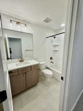 Bathroom featuring vanity, bathing tub / shower combination, a textured ceiling, and light tile patterned flooring