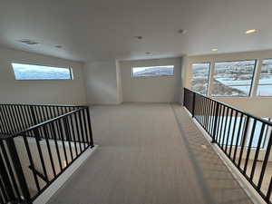 Hallway with light carpet, healthy amount of natural light, recessed lighting, and an upstairs landing