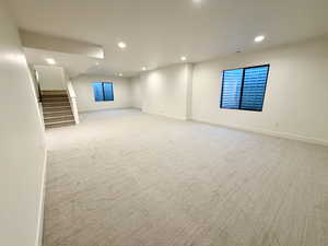 Basement with stairs, recessed lighting, and light colored carpet