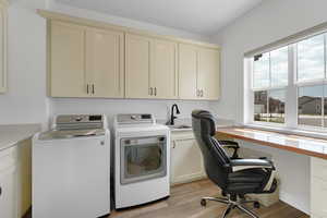 Laundry room with light wood-style floors, cabinet space, washing machine and dryer, and a desk