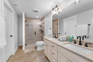 Bathroom with double vanity, a shower stall, and wood tiled floors
