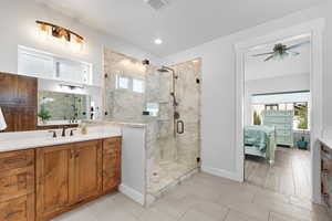 Ensuite bathroom featuring vanity, a marble finish shower, and a ceiling fan
