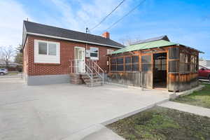 View of front of home with brick siding, roof with shingles, a chimney, and a sunroom