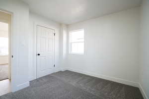 Unfurnished bedroom with dark colored carpet and a textured ceiling