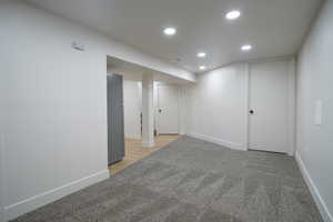 Finished basement featuring light colored carpet, freestanding refrigerator, and recessed lighting