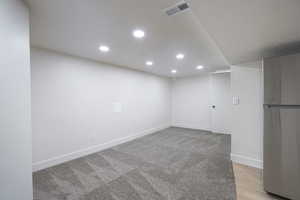 Finished basement featuring freestanding refrigerator, recessed lighting, and light carpet