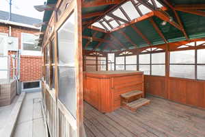 Wooden deck with a sunroom and a hot tub
