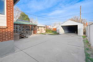 View of patio / terrace featuring an outdoor structure, a detached garage, and concrete driveway