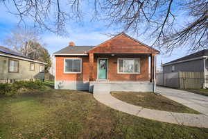 Bungalow-style house with covered porch, brick siding, and a chimney