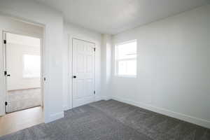 Unfurnished bedroom with dark colored carpet and a textured ceiling