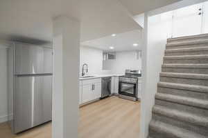 Kitchen with appliances with stainless steel finishes, white cabinets, light wood-type flooring, and recessed lighting