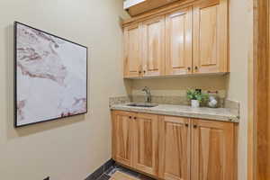 Sink with light brown cabinetry and light stone countertops