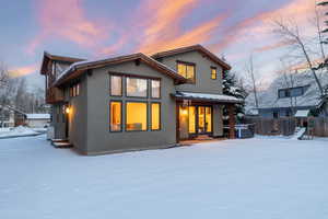 Snow covered house featuring stucco siding and a patio