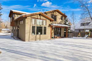 Snow covered back of property with a playground and stucco siding