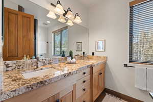Full bathroom featuring double vanity and baseboards