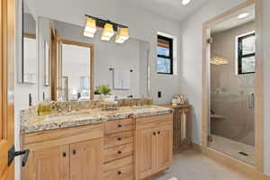 Primary Ensuite bathroom featuring double vanity, a stall shower, and healthy amount of natural light