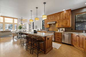 Kitchen featuring healthy amount of natural light, light floors, brown cabinetry, and recessed lighting