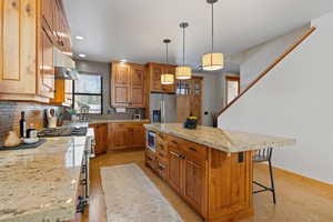 Kitchen with backsplash, a center island, appliances with stainless steel finishes, brown cabinets, and recessed lighting