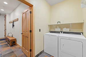 Washroom featuring washing machine and clothes dryer, recessed lighting, and stone tile flooring