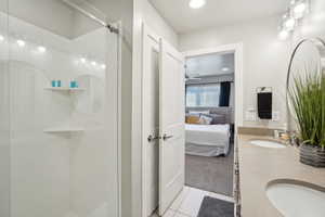 Ensuite bathroom featuring double vanity, light tile patterned floors, light carpet, a shower stall, and recessed lighting