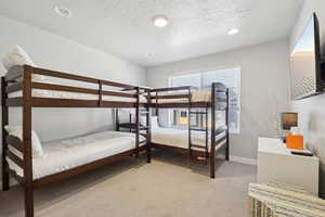 Bedroom with light colored carpet, recessed lighting, and a textured ceiling
